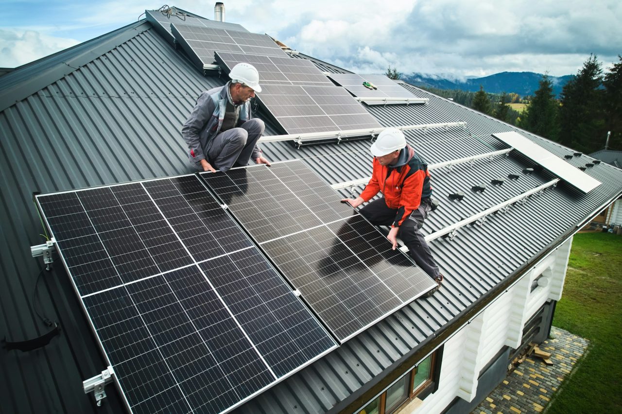 Men workers installing solar panels on roof of house .jpg